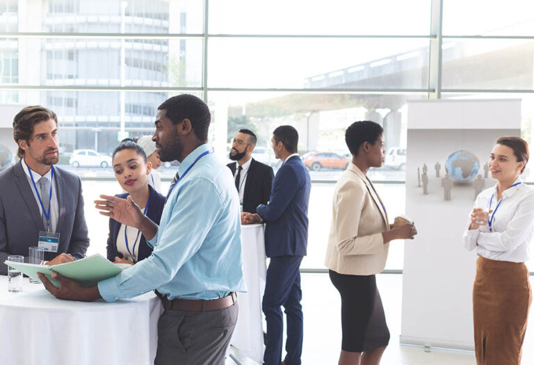 A room of professionals networking in the lobby of a business conference hall.